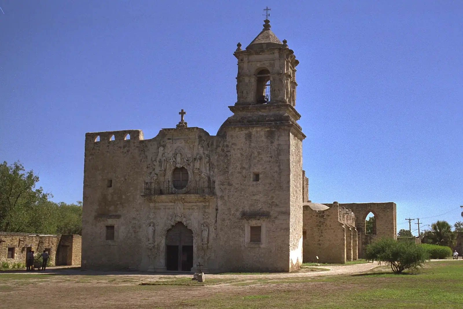 The limestone church and bell tower of Mission San José under a blue South Texas sky